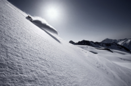 Black and white image of a skier back country skiing with a big snow rooster mid air, shot in black and white. Ross Woodhall - Action & Lifestyle Photography