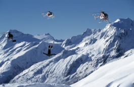 Image from The Rip Curl World Heli Challenge in Wanka New Zealand. Picture of a solo skier doing a somersault with 3 helicopters hoovering over him with the snowy mountains in the background. Ross Woodhall - Action & Lifestyle Photography