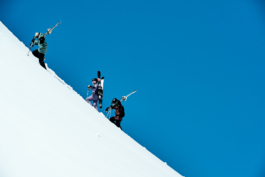 three skiers hiking up the snowy mountain with skis over their shoulders. Ross Woodhall - Action & Lifestyle Photography