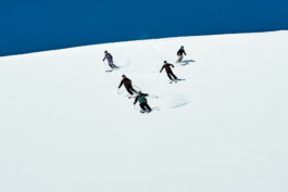 Five skiers in a triangle shape skiing down the hill, off piste. Ross Woodhall - Action & Lifestyle Photography