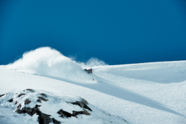 Skier off piste with pole out to make his turn, with snow in the air, with a snow rooster. Ross Woodhall - Action & Lifestyle Photography