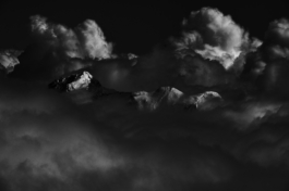 Black and white image of moody clouds with mountain poking through. Ross Woodhall - Action & Lifestyle Photography