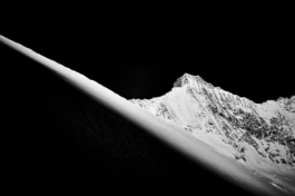Black and white image, sunlight on the mountains in the background with mountain in the foreground with a shaft of light. Ross Woodhall - Action & Lifestyle Photography