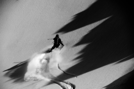 Black and white image of a skier with shadows of a mountain. Ross Woodhall - Action & Lifestyle Photography