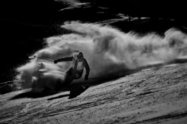 Black and white image of a skier with a snow rooster behind him caught in the wind. Ross Woodhall - Action & Lifestyle Photography