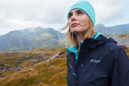 Woman hiker looking out with a bright blue hat matching her hoody in colour. With flyaway hair, in the hills. Ross Woodhall - Action & Lifestyle Photography