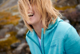 Woman in a zipped hoody, laughing with her hair caught across her face. Ross Woodhall - Action & Lifestyle Photography