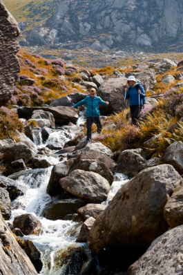 Couple out hiking along a stream with autumnal colours with large rocks. Ross Woodhall - Action & Lifestyle Photography
