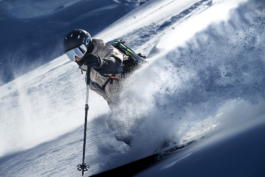 close up of off piste skier mid turn with backpack on with snow flicked up in the wind. Ross Woodhall - Action & Lifestyle Photography