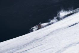 female skier off piste, mid turn with pole out with snow caught in the wind. shot across the slope with a snowy foreground. Ross Woodhall - Action & Lifestyle Photography