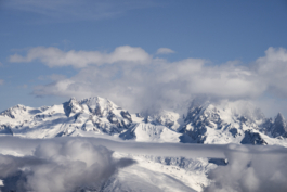 landscape mountain scene with sunlight on mountains with patches of clouds below the mountains and then a gap and above. Ross Woodhall - Action & Lifestyle Photography