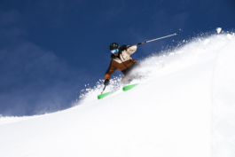 Skier doing a wide turn off piste with snow kicked up Ross Woodhall - Action & Lifestyle Photography